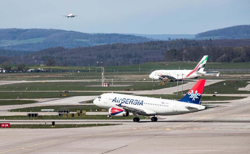 Dynamic scene of airplanes taking off and landing at Zurich Airport on a clear day.